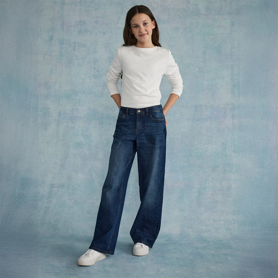 Fehér, texturált felső, széles farmerrel és fehér sportcipőkkel párosítva.