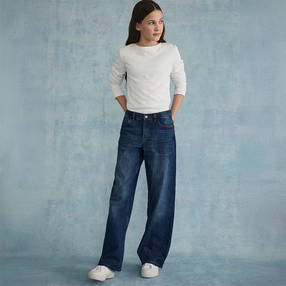 Fehér, texturált felső, széles farmerrel és fehér sportcipőkkel párosítva.